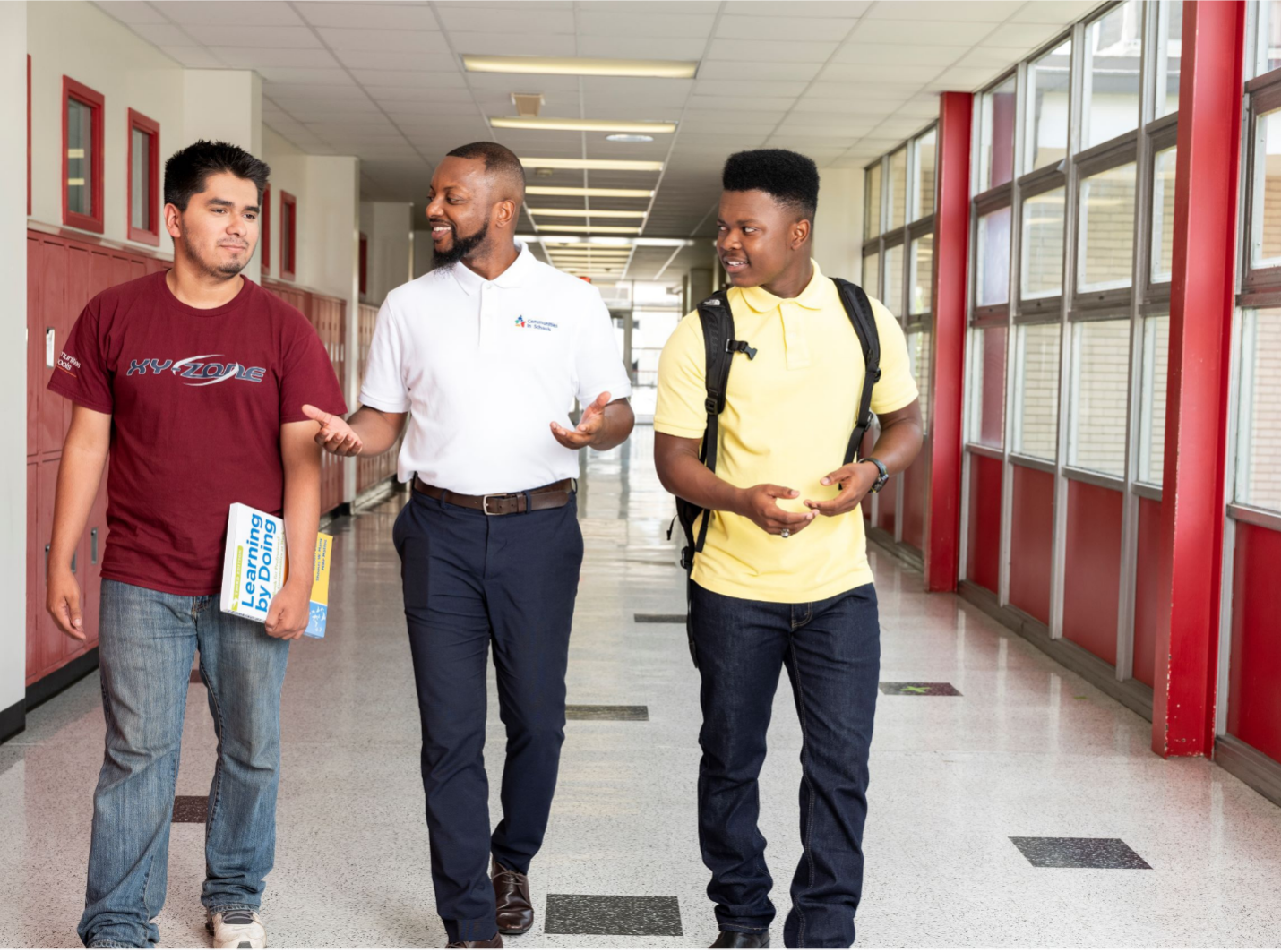 Two students and an adult walk the halls of a high school.