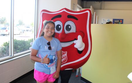 Smiling girl with Salvation Army symbol.